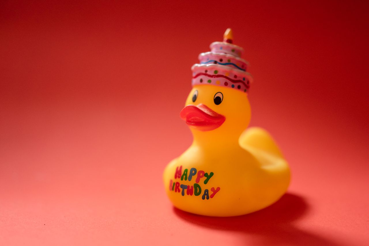 bright yellow rubber duck toy with birthday text on a red background