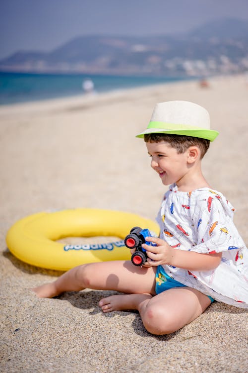 Child Sitting on Beach Sand Beside a Yellow Floater