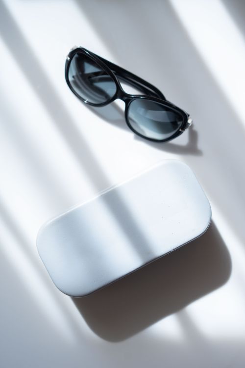 Free Stylish black sunglasses on a white table casting dramatic shadows in sunlight. Stock Photo