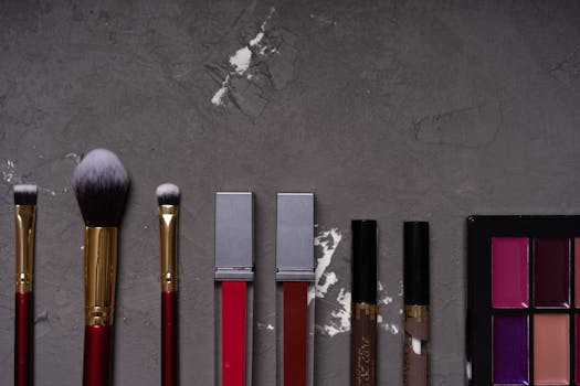 High-quality flat lay of various makeup brushes and cosmetics on textured background.