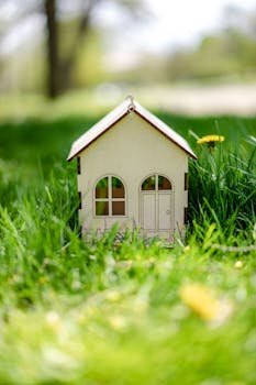 Close-up of a miniature house surrounded by vibrant green grass, emphasizing tranquility.