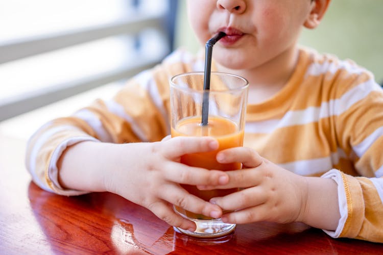 Child Drinking Juice Using A Straw