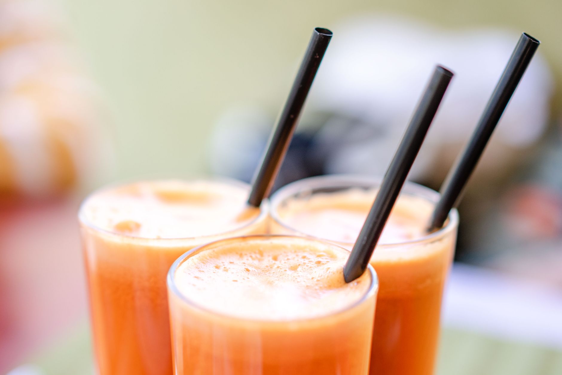 Close-up of refreshing carrot juice served in glasses with black straws, perfect for a healthy snack.