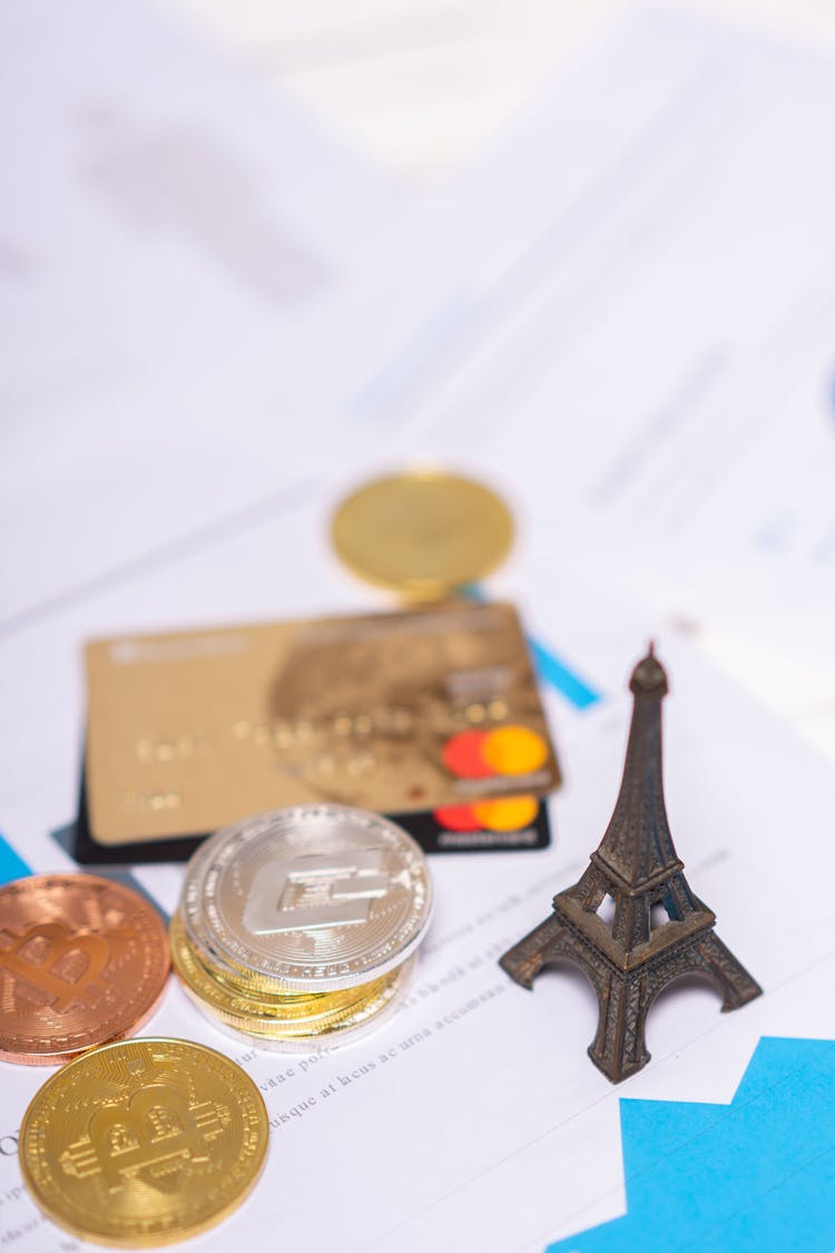 Coins, Bank Cards, And A Miniature Eiffel Tower On Paper Documents