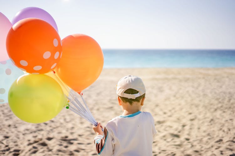 Boy With White Cap Holding Colorful Balloons 