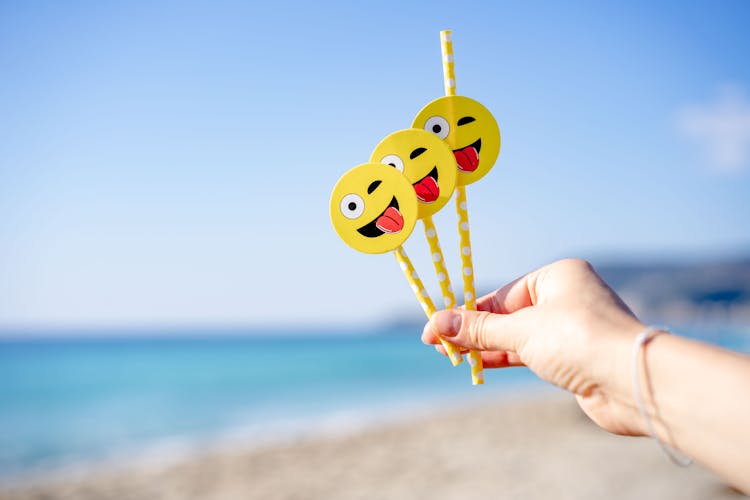 Hand Holding Yellow Straws With Emoji Stickers