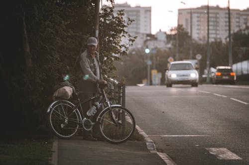 Man with a Bicycle Waiting on Roadside