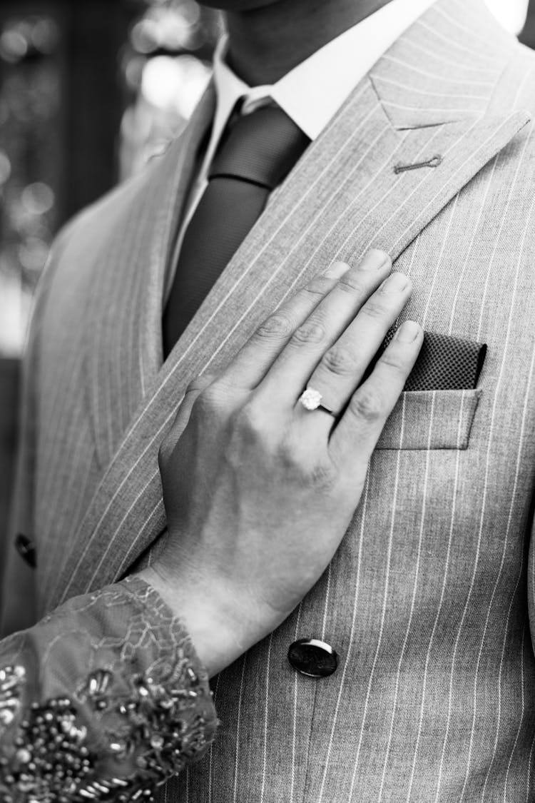 Hand Of A Woman With A Ring Touching The Suit Of A Man