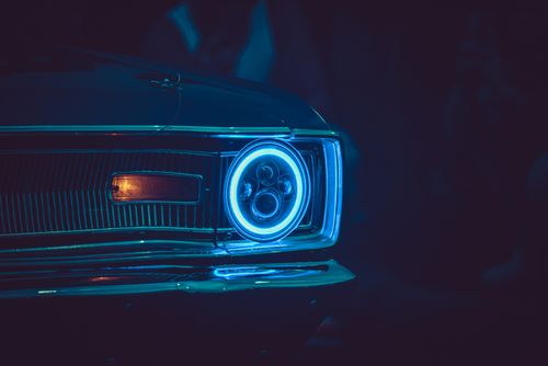 Free Close-up of a car's blue-illuminated headlight in a dark setting, showcasing futuristic design. Stock Photo
