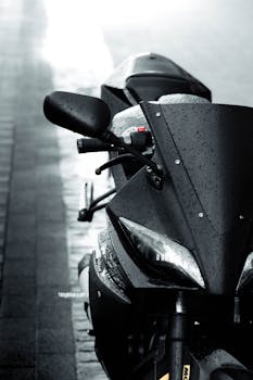 Raindrops on a sleek black motorcycle parked on a wet street for a dramatic urban scene.