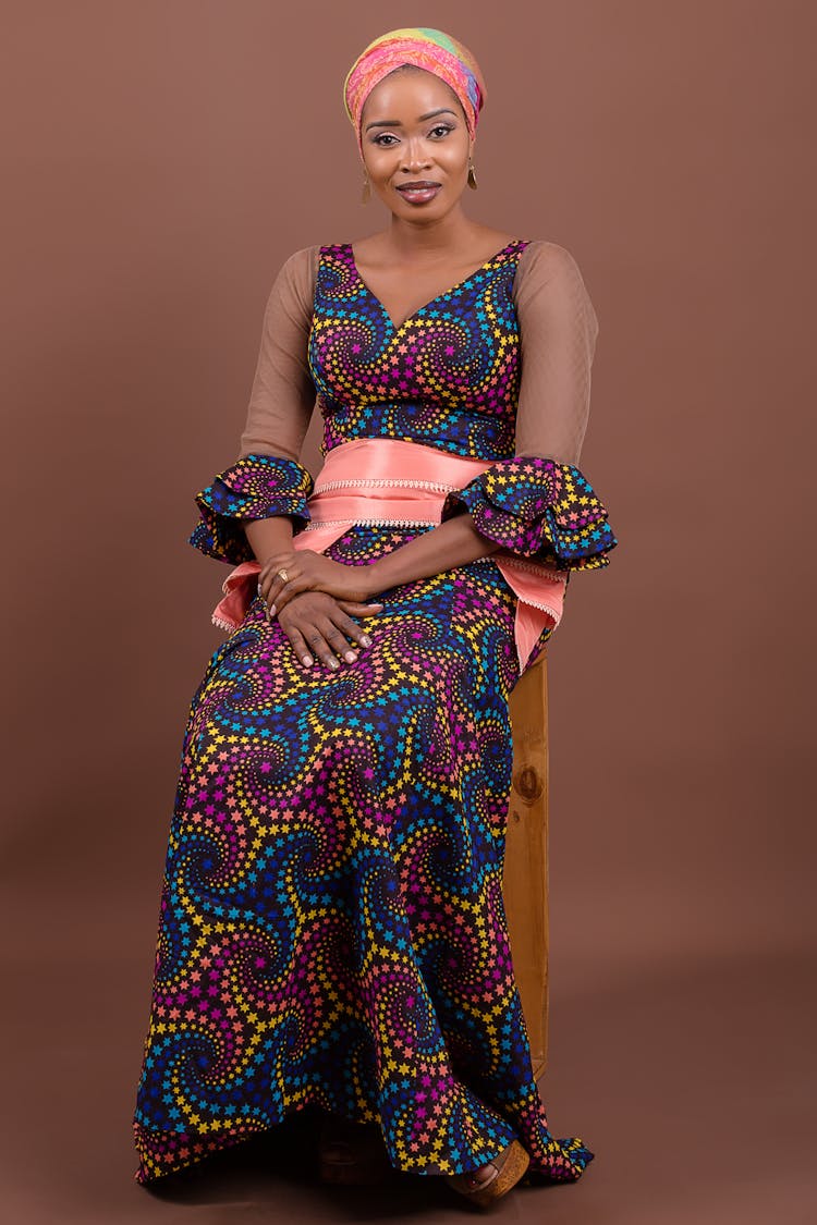 Woman In Traditional Clothes Sitting On Chair In Studio