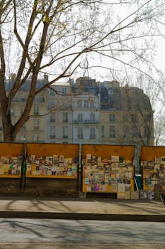 Outdoor book stalls in Paris showcasing a variety of books against a vintage building backdrop.