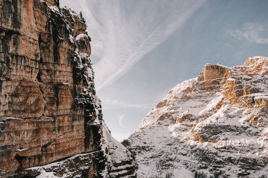 Breathtaking view of snow-covered mountains with a crescent moon in the sky, perfect for nature lovers.