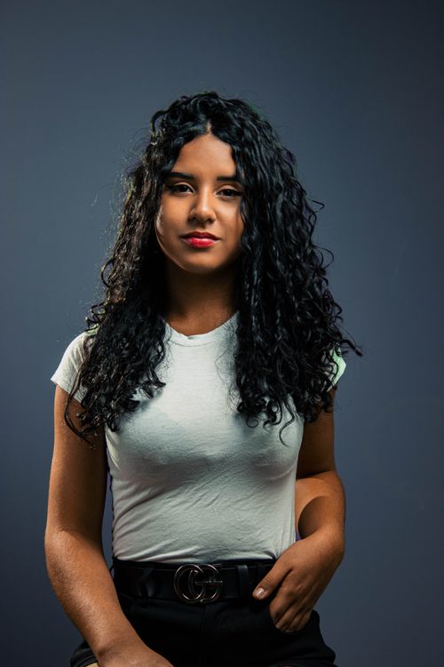 Free Portrait of a smiling woman with curly hair in a white shirt against a gray background. Stock Photo
