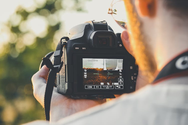 Black Dslr Camera On Person's Hand