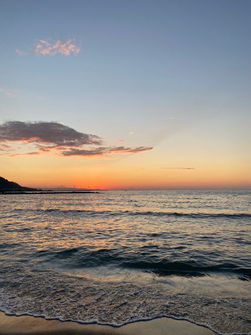 Free Tranquil ocean scene with a vibrant sunset and gentle waves, capturing nature's beauty. Stock Photo