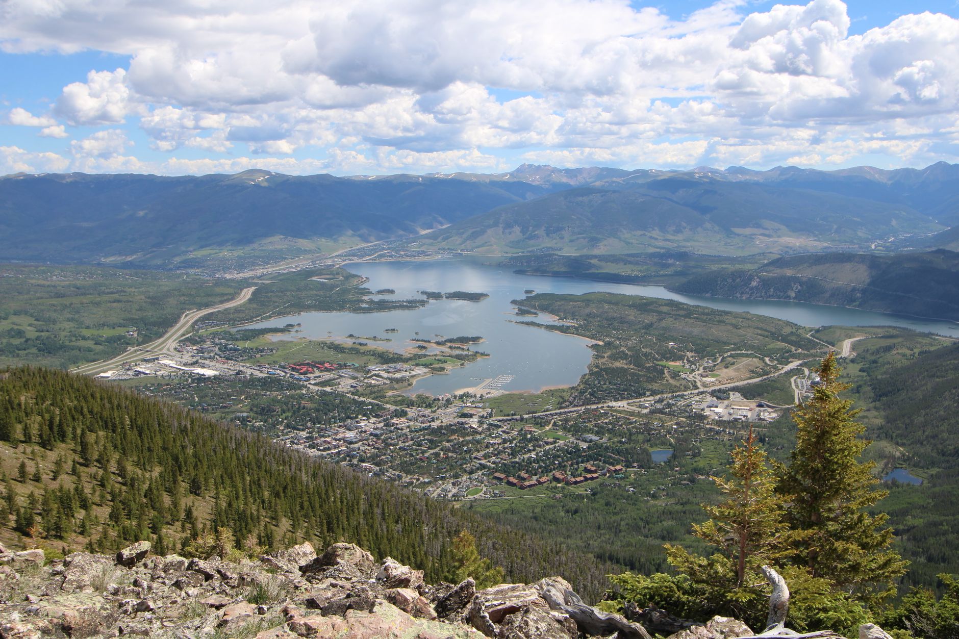 Stunning aerial view of Frisco, Colorado with lake and mountains under a cloudy sky.