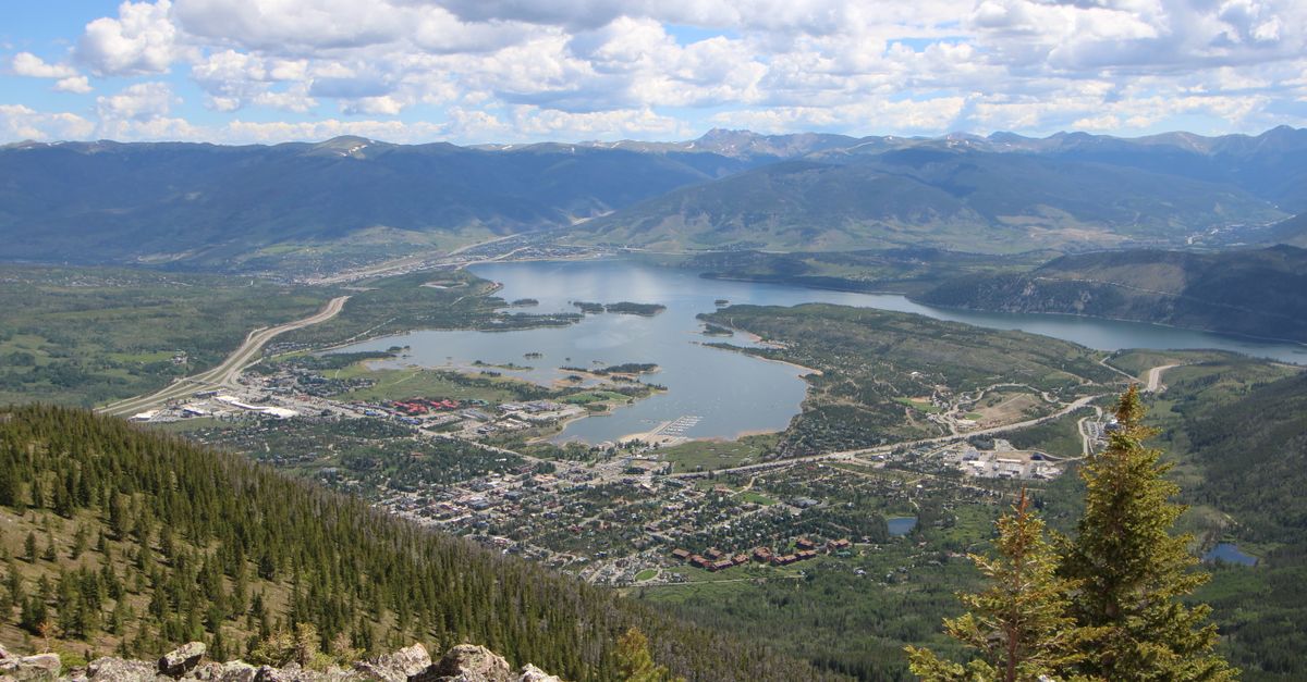 Stunning aerial view of Frisco, Colorado with lake and mountains under a cloudy sky.