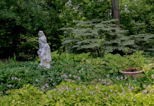 Free A beautiful garden statue adorned with lush foliage and flowers, creating a serene nature scene. Stock Photo
