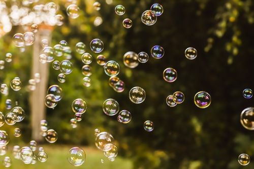 Free Whimsical view of colorful soap bubbles floating against a lush outdoor background. Stock Photo