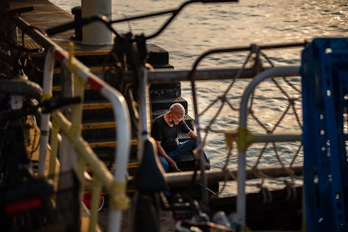 Man Sitting on Stairs on Shore