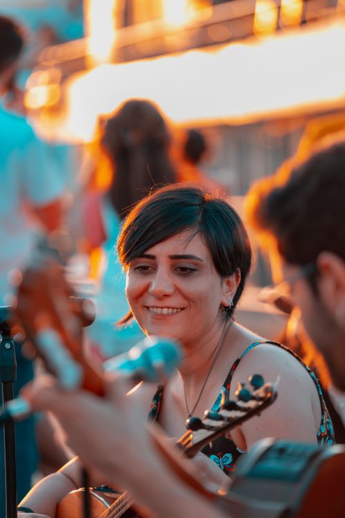 Free A joyful outdoor street music performance featuring smiling musicians playing guitars at sunset. Stock Photo