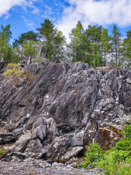 Free Striking rocky cliff with lush green trees under a clear blue sky, perfect for nature enthusiasts. Stock Photo