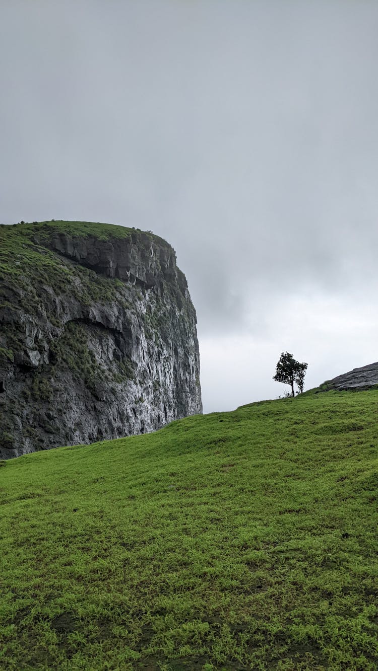 Overcast Over Grass Meadow And Rock Formation