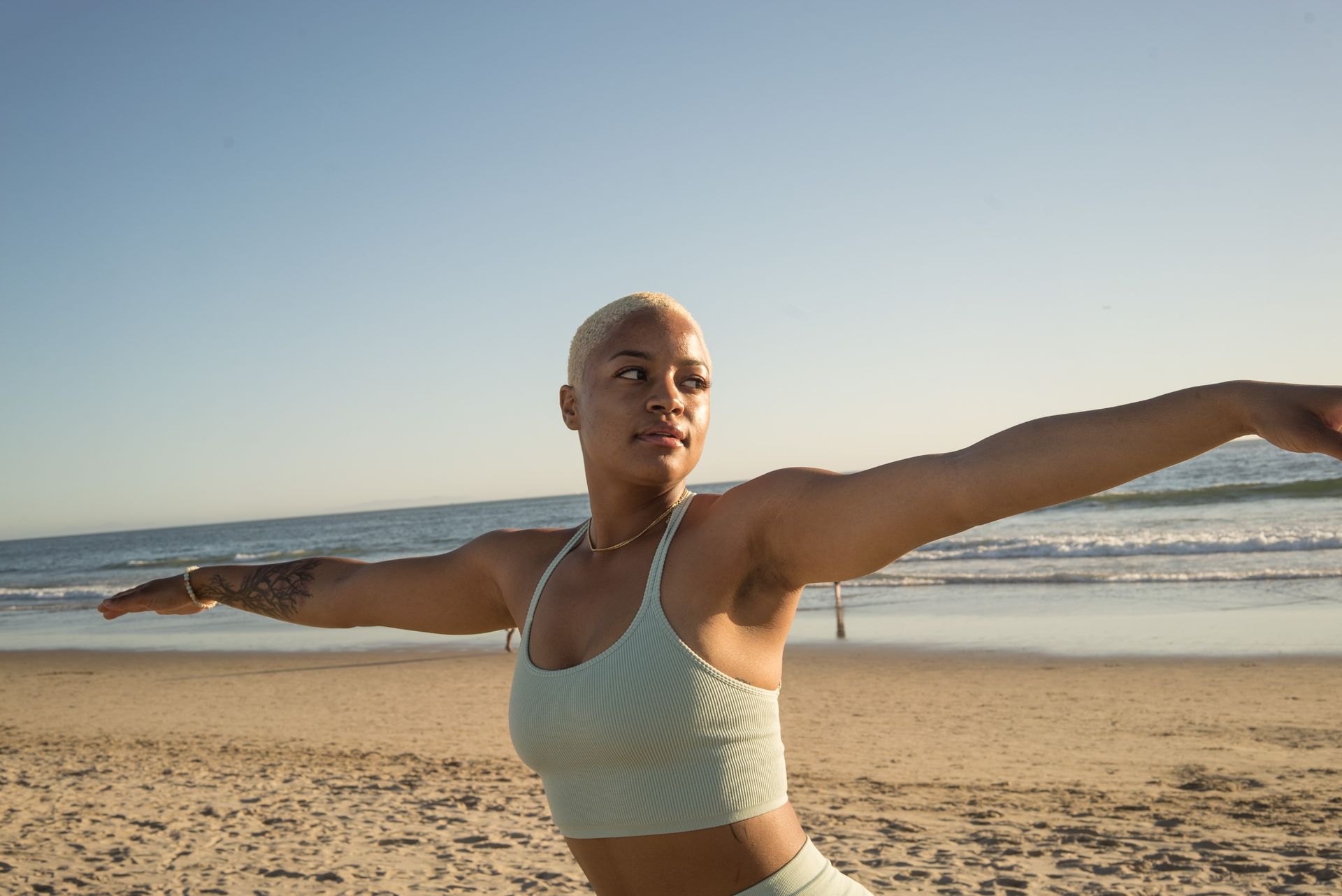 A woman performs yoga on a sunny day at Santa Monica Beach, embracing fitness and relaxation.