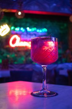 Close-up shot of a colorful cocktail with neon lights in a trendy bar, creating a lively ambiance.