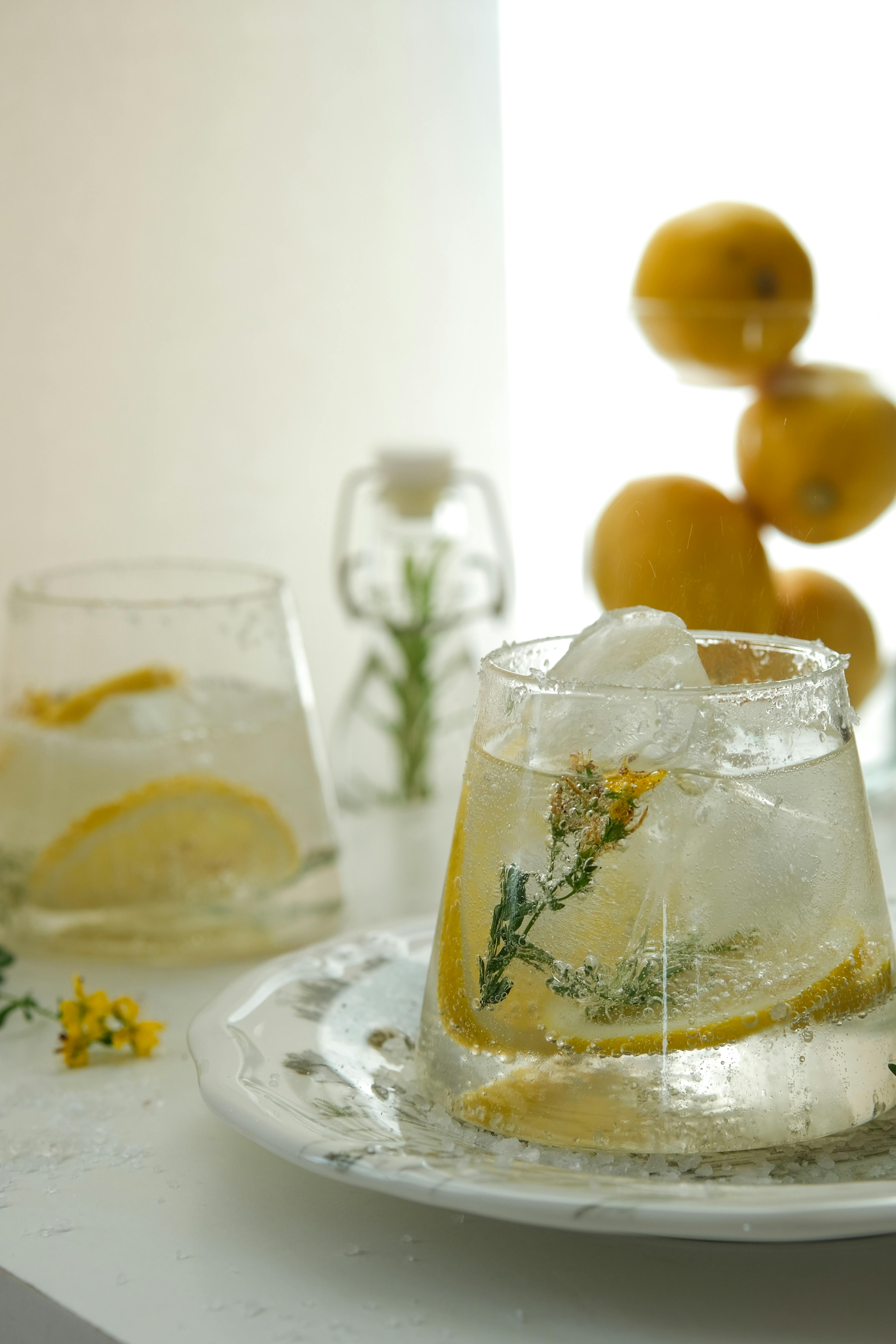 Chilled lemonade with lemon slices and floral garnish in a glass, perfect for a refreshing summer drink.
