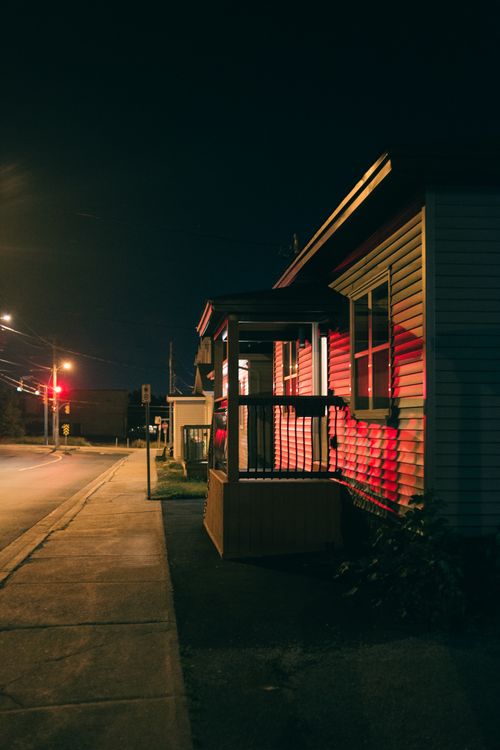 Free Illuminated house on a quiet suburban street at night, capturing a moody urban ambiance. Stock Photo