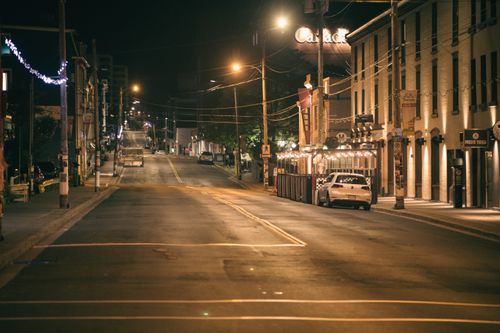 Free A serene urban street captured at night with soft lighting and a parked car. Stock Photo