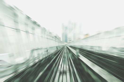 Abstract motion blur view of urban train tracks in a city setting, indicating speed and movement.