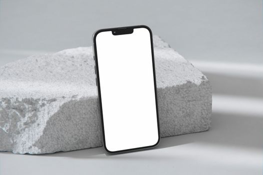 Modern smartphone with a blank white screen positioned against a concrete block. Ideal for showcasing apps or designs.