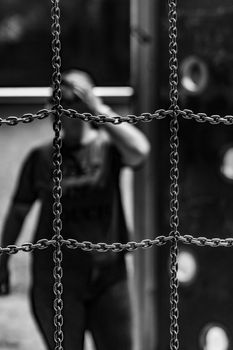 Artistic black and white photo of chain links with a blurred person in the background.