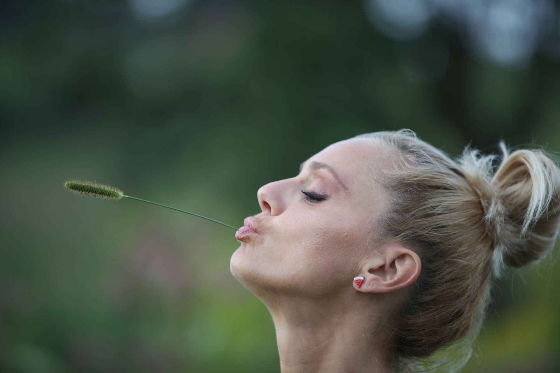 A serene profile of a young blonde woman outdoors embracing nature.