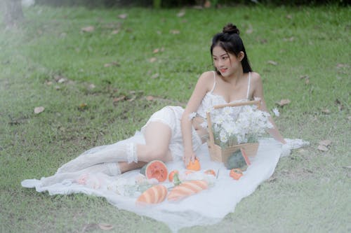 Beautiful Woman in White Outfit Lying on White Picnic Blanket