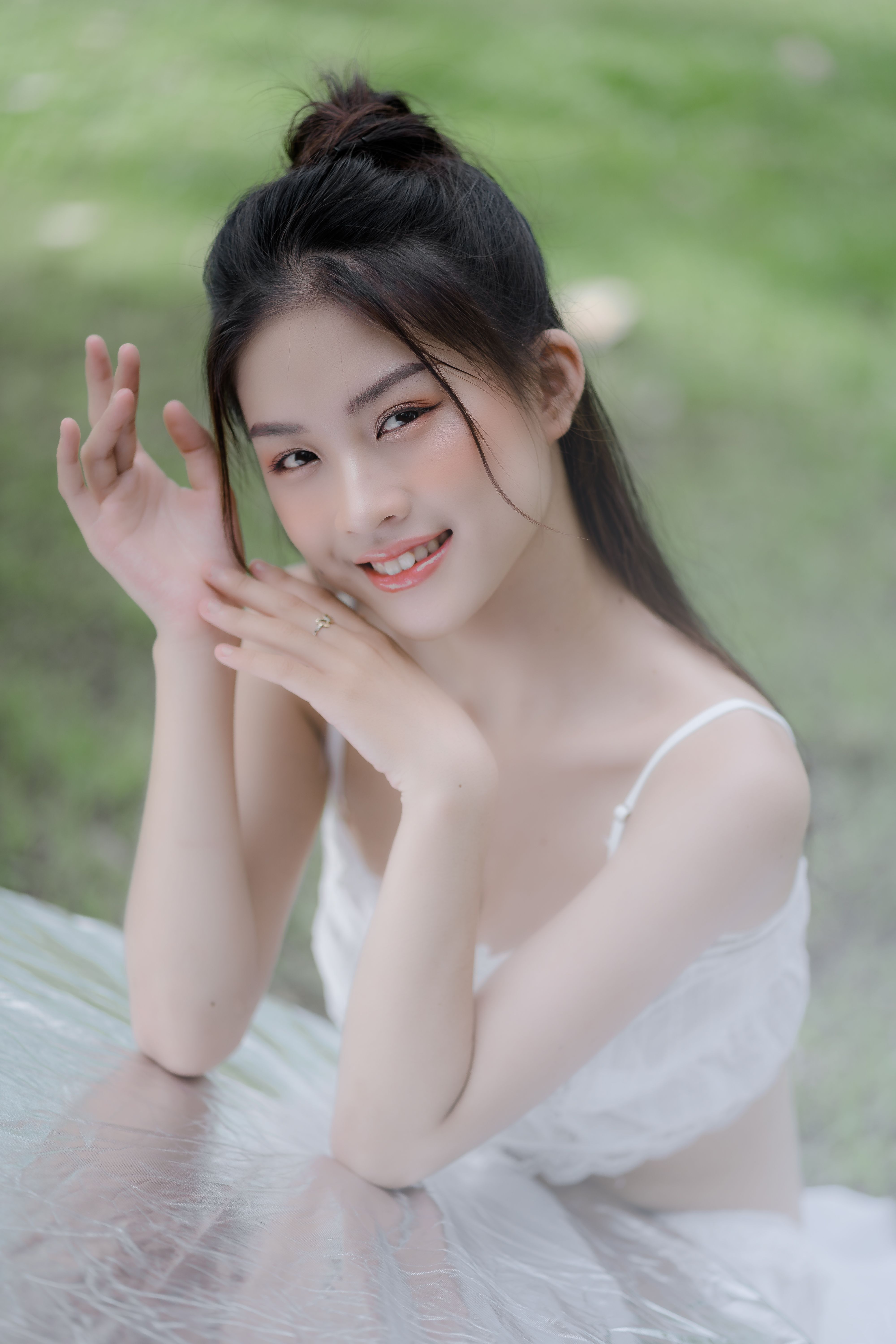 A beautiful woman smiling and posing gracefully in a natural outdoor setting.