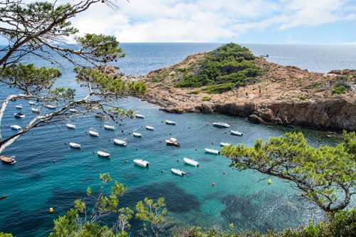 Free A breathtaking aerial view of boats anchored in a clear blue bay surrounded by lush hills. Stock Photo