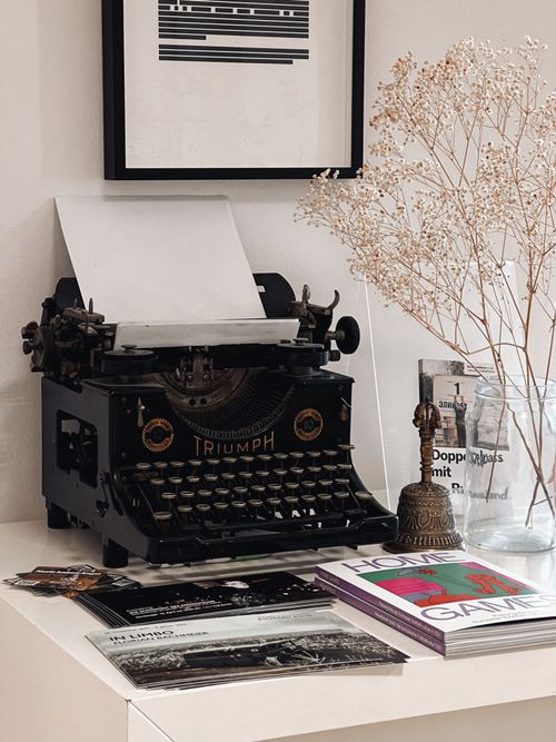 Free A vintage typewriter surrounded by artistic decor and magazines in a minimalist setting. Stock Photo