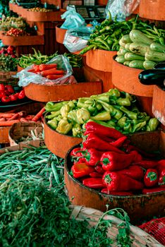 A colorful display of fresh vegetables at a market, showcasing peppers, zucchini, and more.
