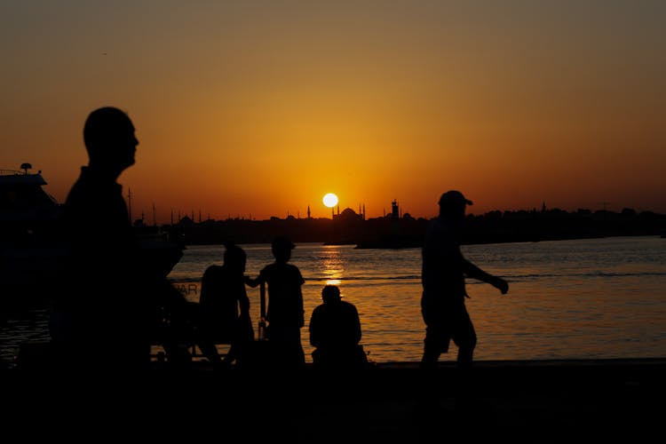 Silhouette Of People On Beach During Sunset