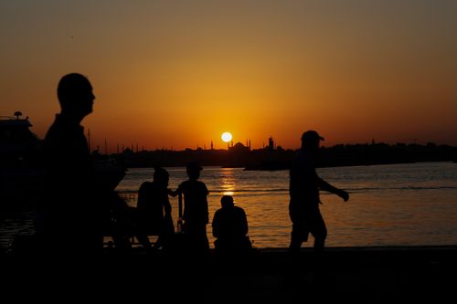 Free Silhouettes of people by the water in Istanbul at sunset, with a vivid orange sky. Stock Photo