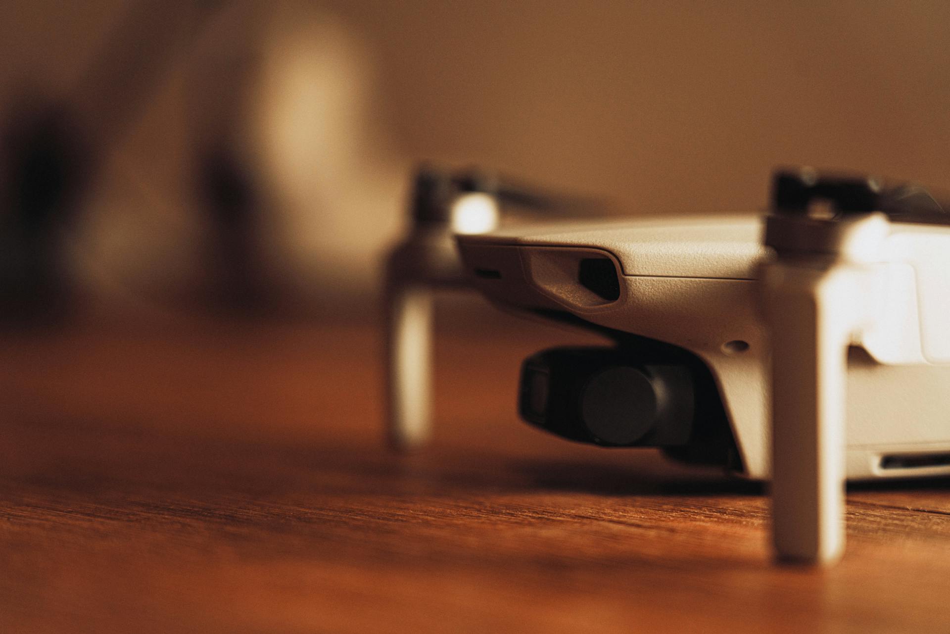 A detailed close-up view of a modern drone camera positioned on a wooden surface.