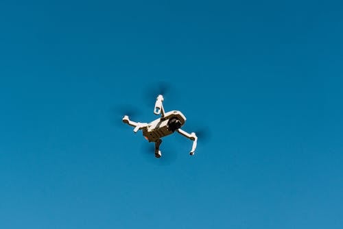 Low-Angle Shot of a White Drone Camera Flying in the Blue Sky