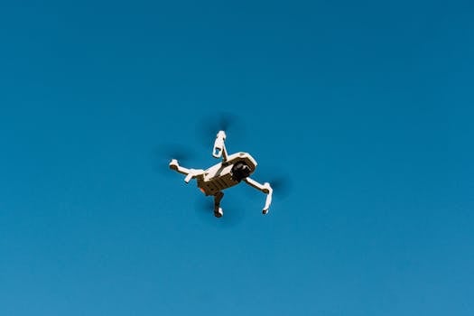 A drone flying against a clear blue sky, capturing aerial views.