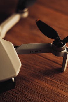 Detailed view of a Mini 2 drone arm and propeller on a wooden surface, showcasing design.