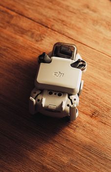 Top-down close-up of a compact gray drone on a wooden surface, showcasing detail and texture.