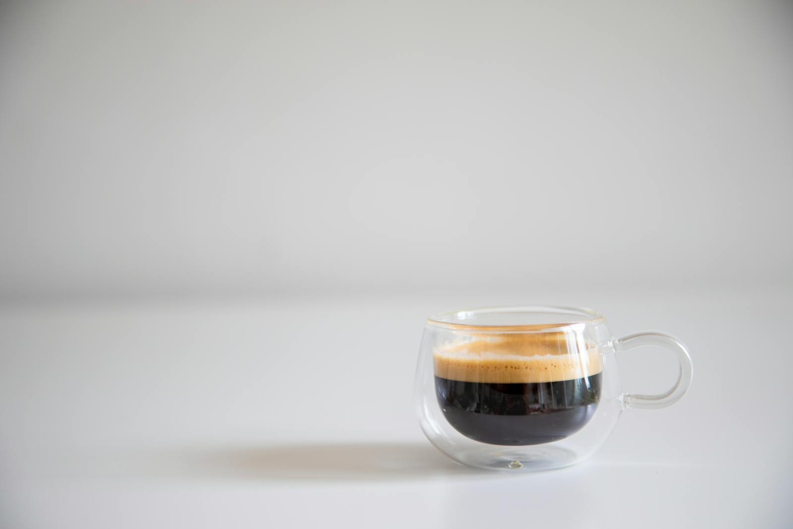 Americano-style black coffee in glass cup with a crema ring